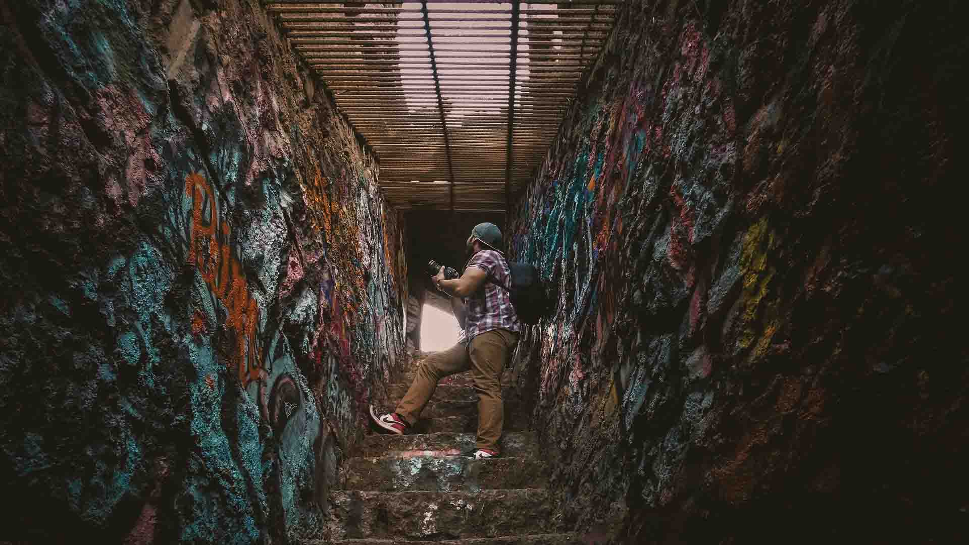 man with camera in a graffiti-ed stairwell