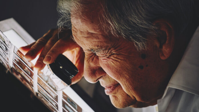 A man looking at the length of film slides